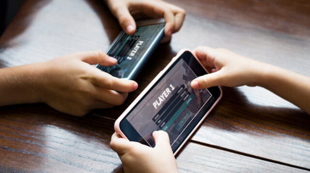 Little boy playing a mobile game against his sister