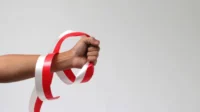 Pria dengan kepalan tangan memegang pita merah dan putih dengan ruang salinan kosong terisolasi pada latar belakang putih.