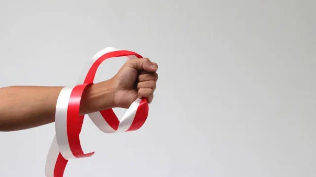 Pria dengan kepalan tangan memegang pita merah dan putih dengan ruang salinan kosong terisolasi pada latar belakang putih.